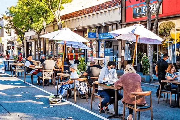 A group of people sitting at tables outside