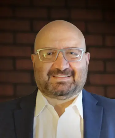 A man with glasses and bald head wearing a suit.