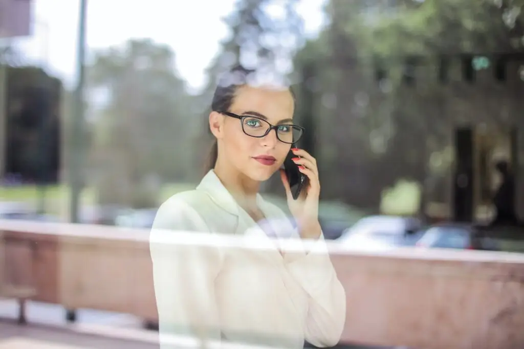 A woman in glasses talking on the phone.